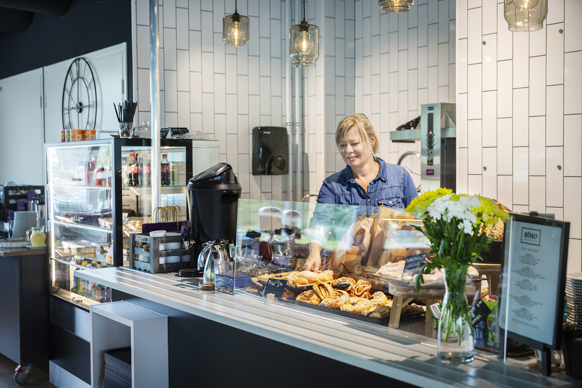 Ravintola Aiho, nainen hymyilee myyntitiskin takana.