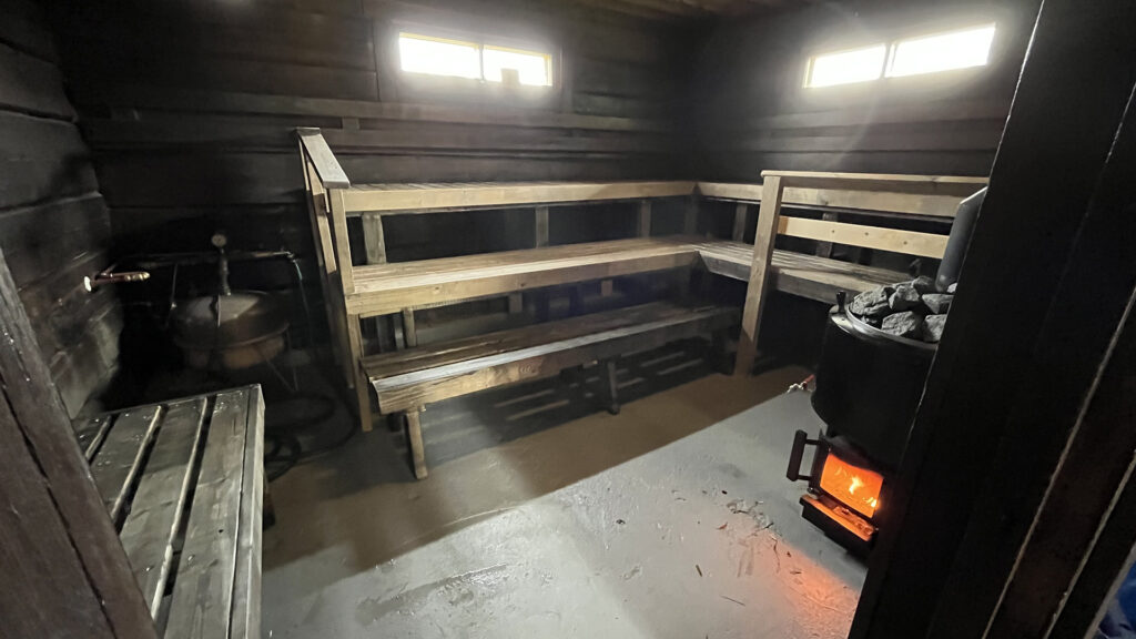 Kiviniemen tilan sauna sisältä kuvattuna, saunan lauteet ovat tyhjät, tulipesästä hohkaa tulen lämpö.